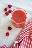 A red berry smoothies with raspberries in a glass