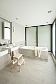 Minimalist designer bathroom with sinks below mirror in niche and bathtub