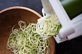 Courgette noodles being made with a spiral cutter