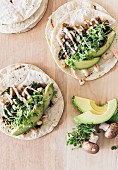 Vegetarian tacos with vegan mayonnaise on a kitchen table with avocado, mushrooms and beans sprouts