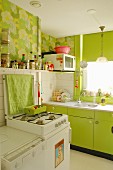 Spring atmosphere in fitted kitchen - lime green cupboard fronts and 70s-style floral wallpaper
