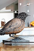 Vogelfigur aus Metall auf Steinplatte