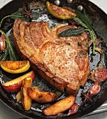 Fried pork chop with apples and sage in a pan