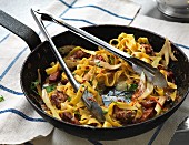 Tagliatelle with sausage and cheese in a pan