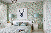 Blumentapete mit Magnolienblüten in ländlichem Schlafzimmer, über Doppelbett Bild mit Hirschportrait