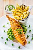 Battered fish on a bed of mushy peas with chips