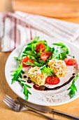 Salad with goat's cheese in an almond crust, rocket, tomatoes and balsamic sauce