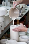 Ceramic workshop - person pouring slip and blanks of various sizes