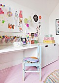 Holzstuhl mit abblätternder Farbe vor Schreibtischablage in Mädchenzimmer mit rosafarbenem Dielenboden
