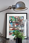Still-life arrangement of black-framed picture, retro table lamps an glass vessels