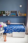 Weißes Bett mit Bettschubladen in Jungenzimmer mit nostalgischem Spielzeug und blauer Wand