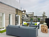 Elegant grey sofas and sandstone elephant ornaments on roof terrace with wooden decking
