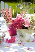 Romantic table arrangement with napkin decoupage pots, floral tablecloth and pink summer flowers