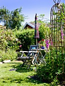 Wooden chair and folding table in summery garden with vintage obelisk and parasol