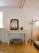 Brennende Kerzen im Kerzenhalter vor Spiegel auf Konsolentisch mit geschnitzten Beinen in Weiß, seitlich Vintage Stehleuchte aus schmiedeeisernem Gestell