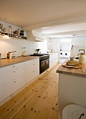 Kitchen counter with white base units in spacious kitchen with wooden floor and open doorway leading into utility room
