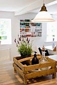 Vintage bottle, black soap dispenser and potted lavender in wooden crate below pendant lamp with retro glass lampshade