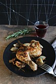A chicken leg with onions and rosemary served with a glass of red wine