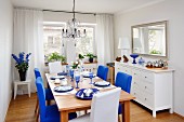 Dining room furnished in white with bold accents of magenta and royal blue