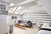 Bright interior with exposed roof structure, grey sofa against grey and white striped back wall and pale wooden table