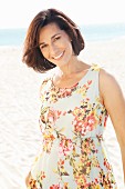 Brunette woman wearing floral summer dress on beach