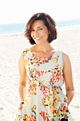 Brünette Frau in Sommerkleid mit Blumenmuster am Strand