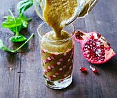 Fig and apple smoothie with pomegranate seeds, green kale and baby spinach