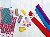 Utensils for crafting a wind chime: cardboard tubes, coloured paper, crepe paper and circle punch
