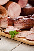 Various types of meat and bacon on a wooden board