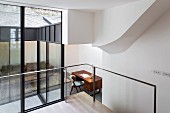 View through glass wall into living room with sofa and desk in extension