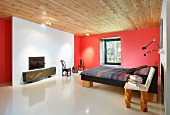 weiße Kaminwand in rotem Schlafraum, Bett und Stuhl auf Holzklotz-Füssen