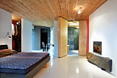 Purist bedroom in modern building: rustic stone slab under glass-fronted fireplace