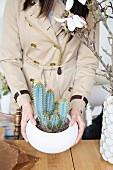 Woman holding bowl of cacti
