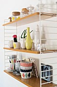 Crockery with colourful, retro patterns, vases and storage jars on wall-mounted String shelves