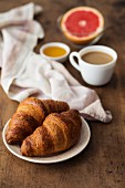 Croissants mit Kaffee, Honig und Grapefruit zum Frühstück