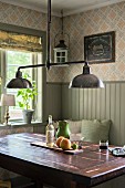 Retro pendant lamp with chrome lampshades above solid-wood table in corner of dining room