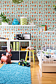 Blue flokati rug in front of half-height shelving and bed with white metal frame against wall with patterned, children's wallpaper