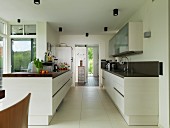 Two facing counters in open-plan kitchen with large floor tiles and doorway leading to foyer in background