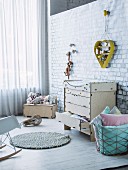 Baby-changing cabinet and wire basket of cushions below heart-shaped yellow shelving unit hung on wall