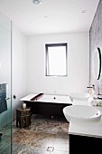 Modernes, schwarz-weisses Bad mit Travertinboden, orientalisches Ablagetischchen und Wannentablett aus Holz