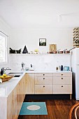 Moderne reduzierte Küchenecke mit Holzfronten und weißer Küchenarbeitsplatte