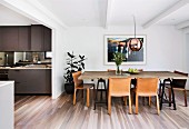 Brown leather chairs around rustic dining table in open-plan kitchen