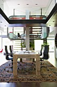 Futuristische Innenarchitektur mit Homeoffice-Bereich in Luxuswohnung, im Vordergrund rustikaler Holztisch mit Eames-Bürostühlen