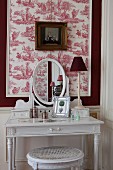 Dressing table against red and white toile de jouy wallpaper in bedroom