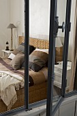 View of bed with striped bed linen in various shades of brown through open interior window