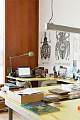 Hellgelbe Tischplatten in U-Form, Retro Tischleuchte, im Hintergrund grafische Zeichnungen von Insekten im Arbeitszimmer