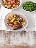Oven-roasted pork loin with onions and garlic served with couscous with mixed barbeque guests and rocket