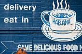A blue-painted brick wall with a coffee advert in white
