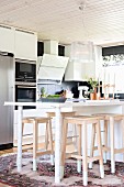 Modern counter-height table and wooden bar stools in open-plan kitchen