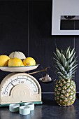 Lemons and melon on vintage kitchen scales on dark grey surface